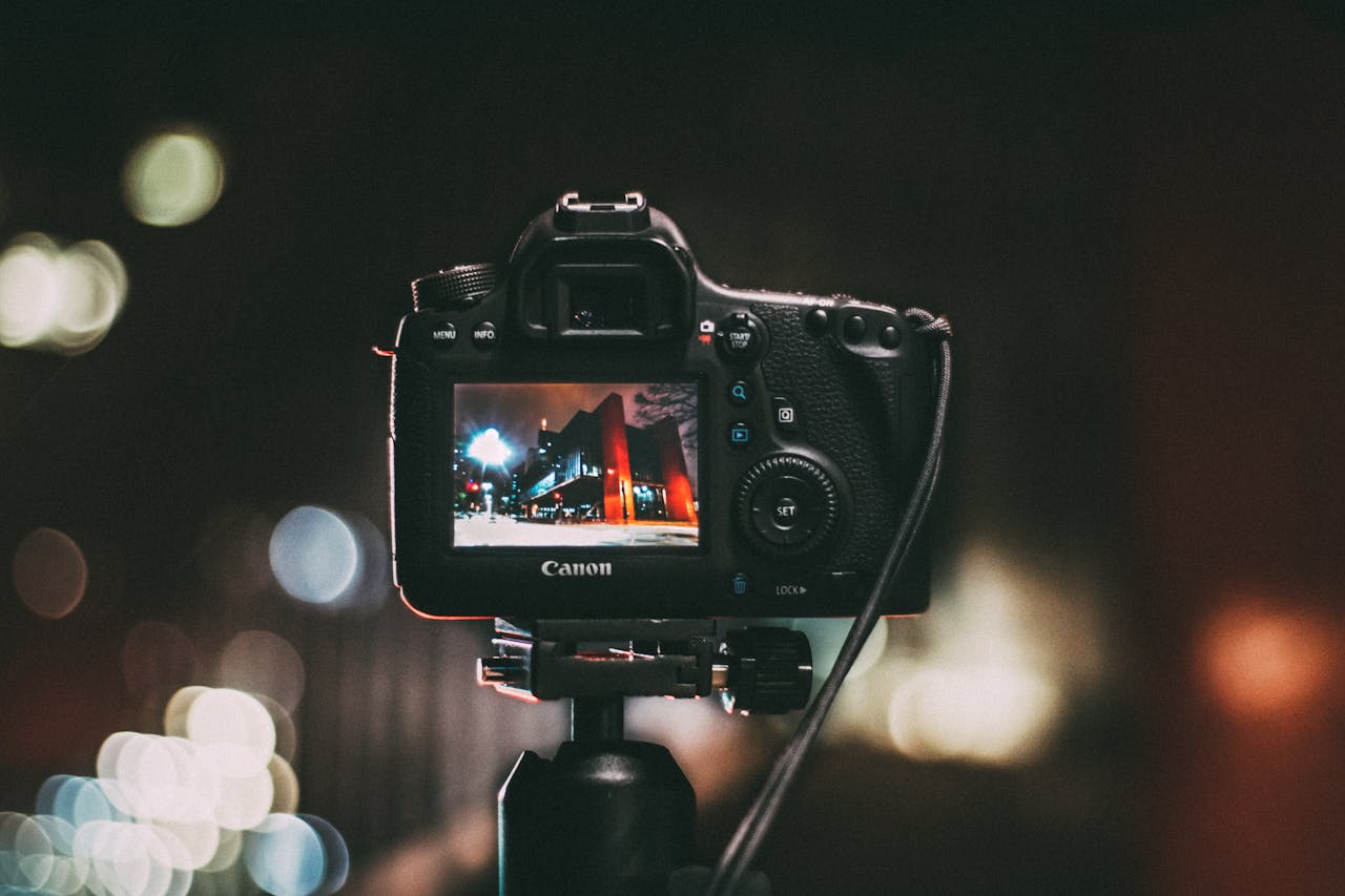 Close-up of a camera capturing a vibrant urban scene at night with a blurred bokeh background.